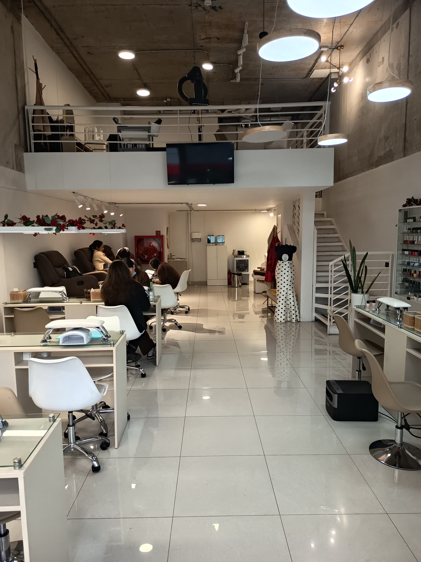 Interior de El Salón de las Uñas en Ñuñoa: espacio blanco de doble altura con estaciones de manicure